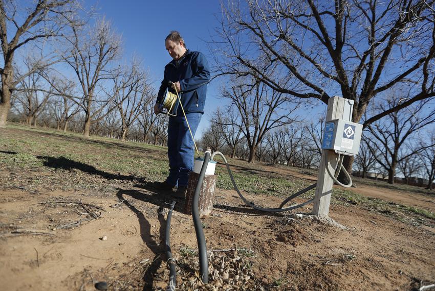Field Technician Supervisor Billy Barron uses e-line water level meter to check the level of a water well in a pecan orchard in Lubbock County. Barron was checking water levels near the at the High Plains Underground Water Conservation office Friday, Dec. 13, 2023.