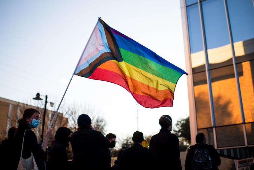 A protestor waves a pride flag during a protest outside of the G. Brint Ryan College of Business at the University of North Texas in Denton on March 23, 2022.